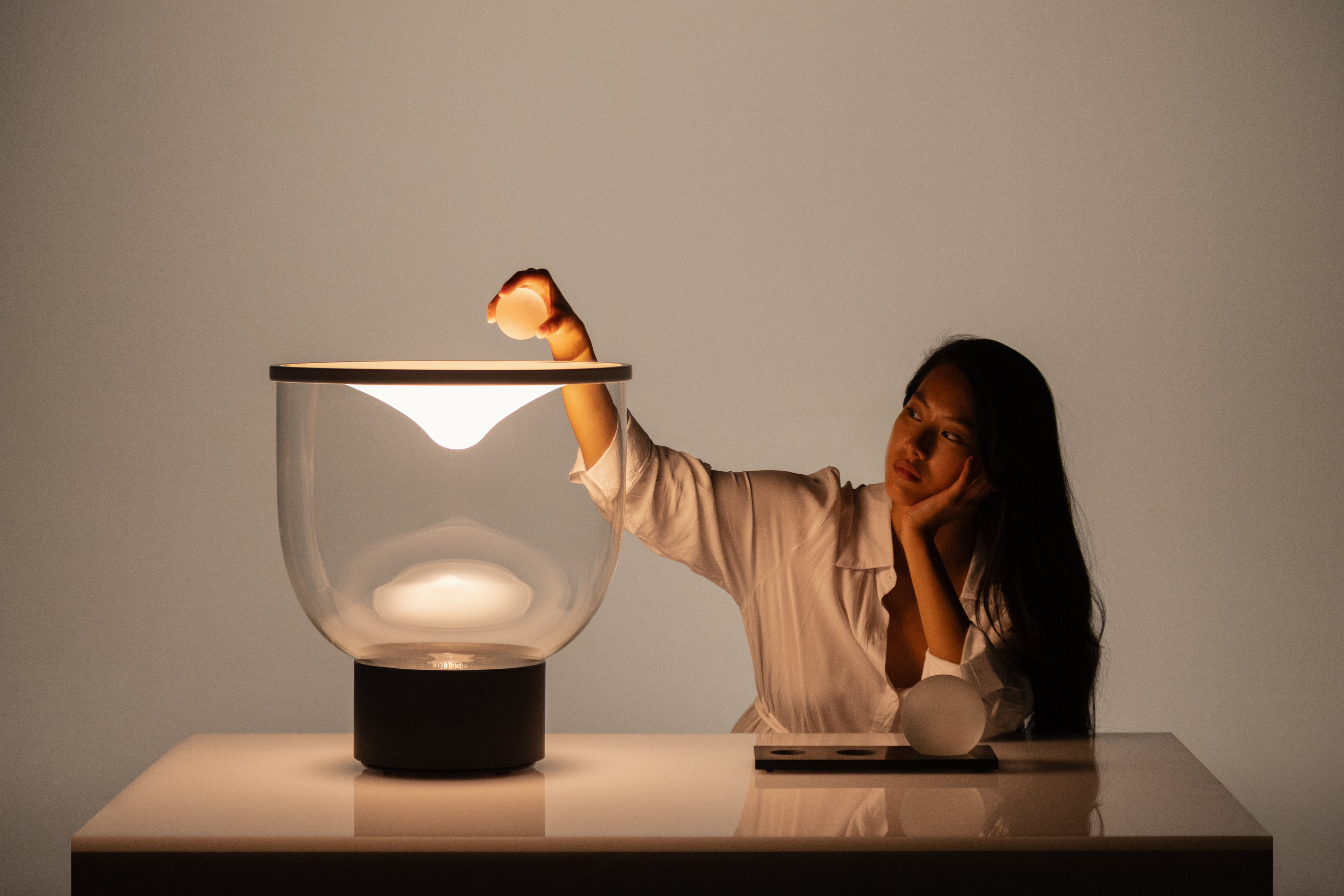 Stolní lampa GRAMMOLUCE se skleněným stínidlem a černým podstavcem.