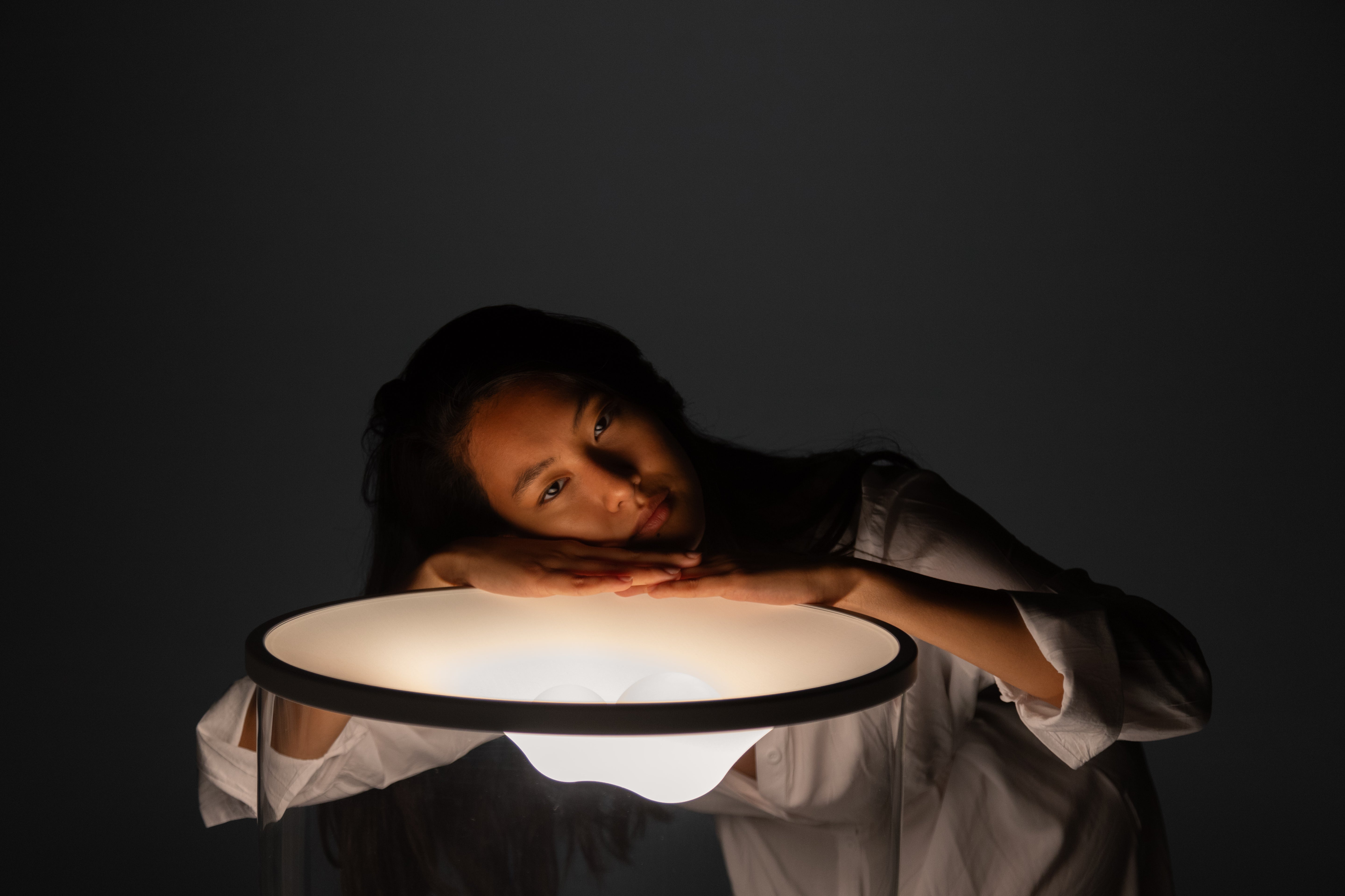 Stolní lampa GRAMMOLUCE se skleněným stínidlem a černým podstavcem.