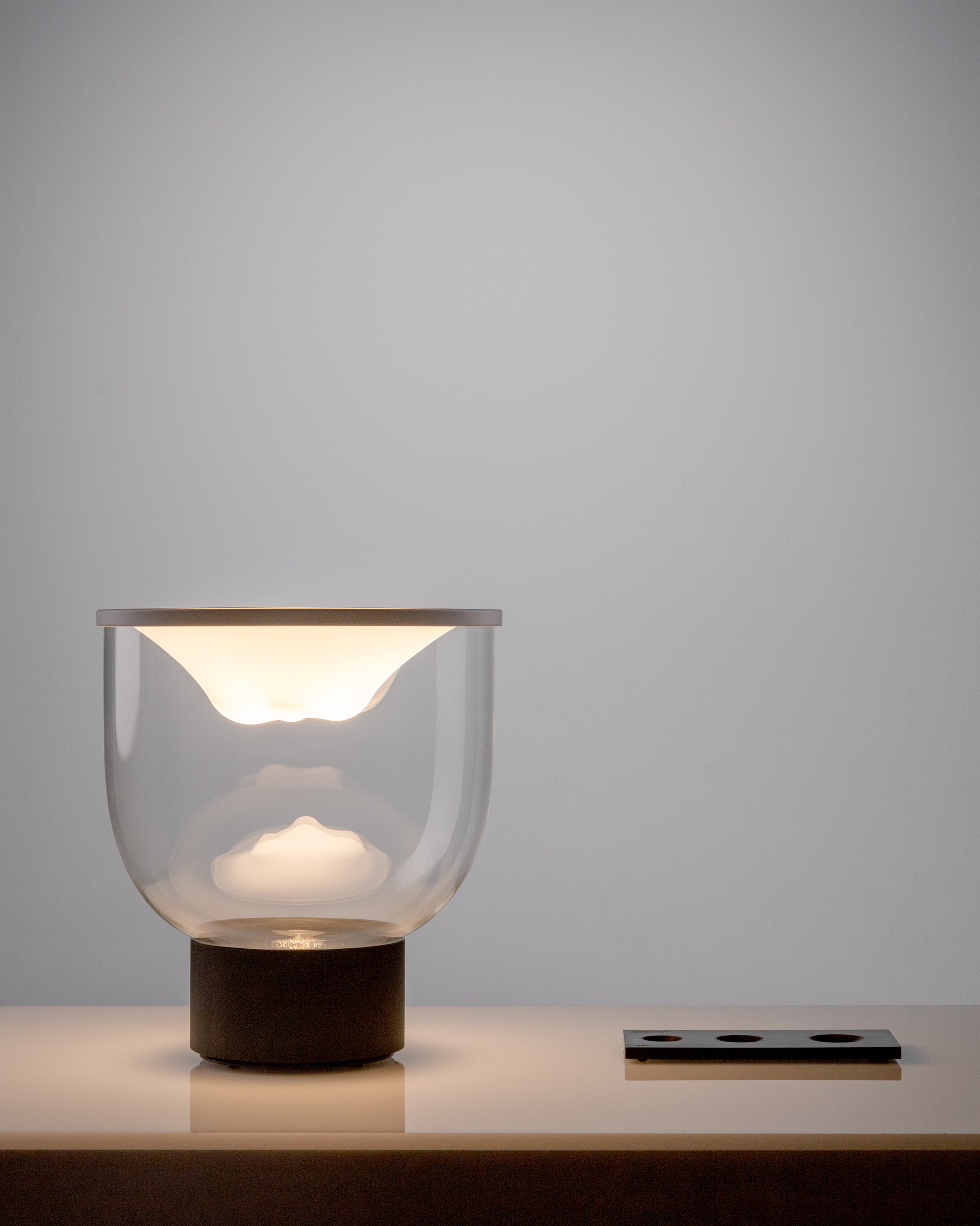Stolní lampa GRAMMOLUCE se skleněným stínidlem a černým podstavcem.