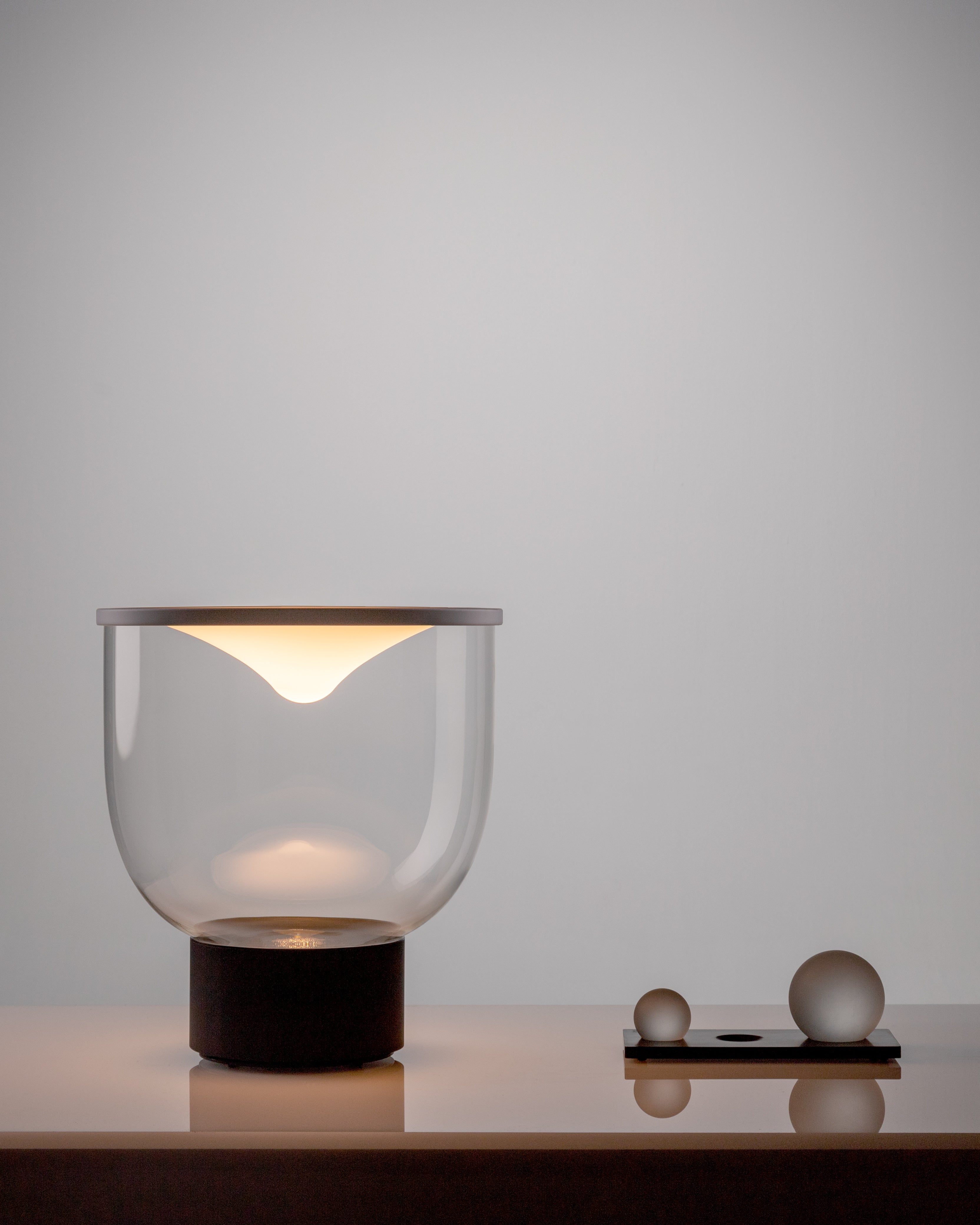 Stolní lampa GRAMMOLUCE se skleněným stínidlem a černým podstavcem.