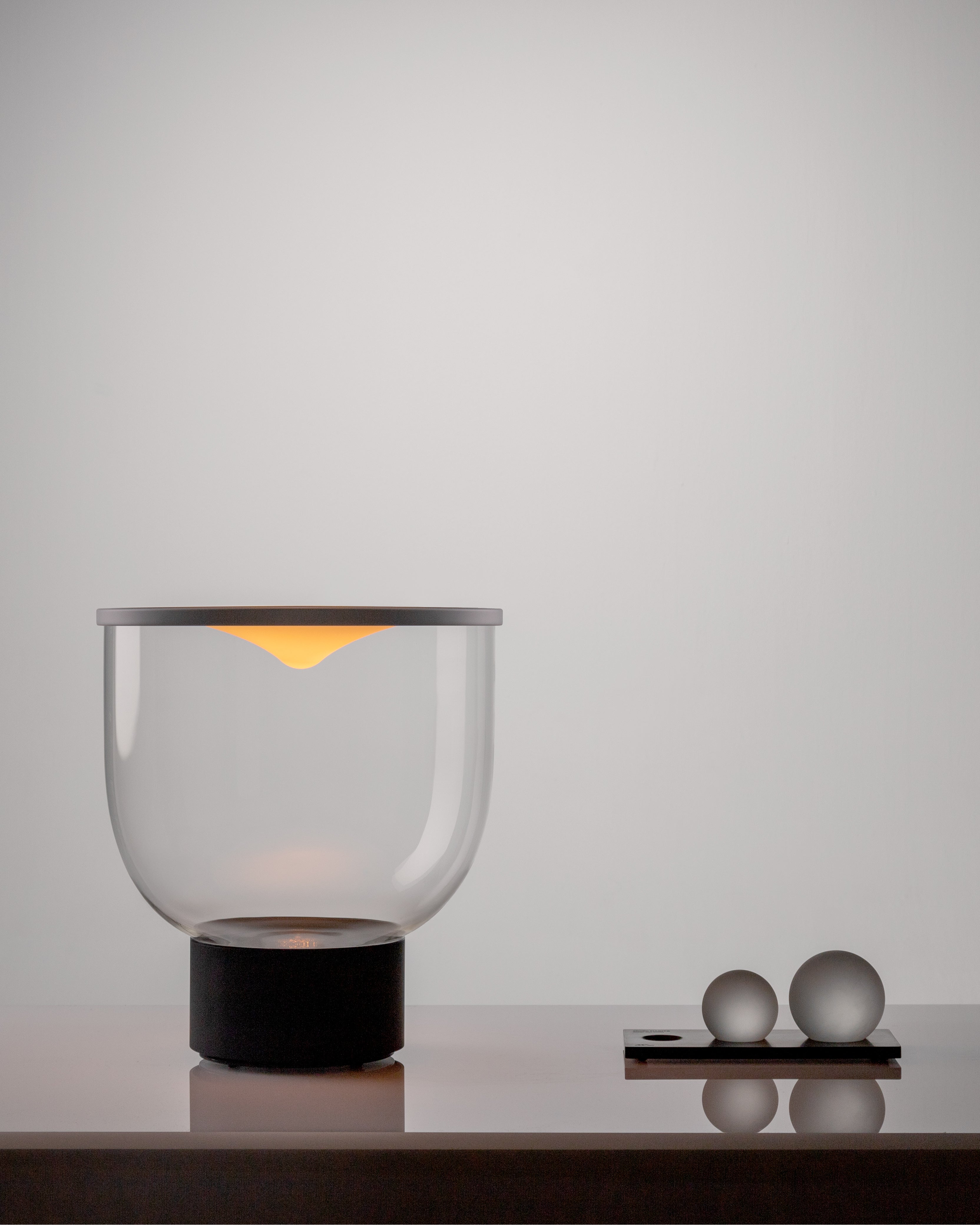 Stolní lampa GRAMMOLUCE se skleněným stínidlem a černým podstavcem.