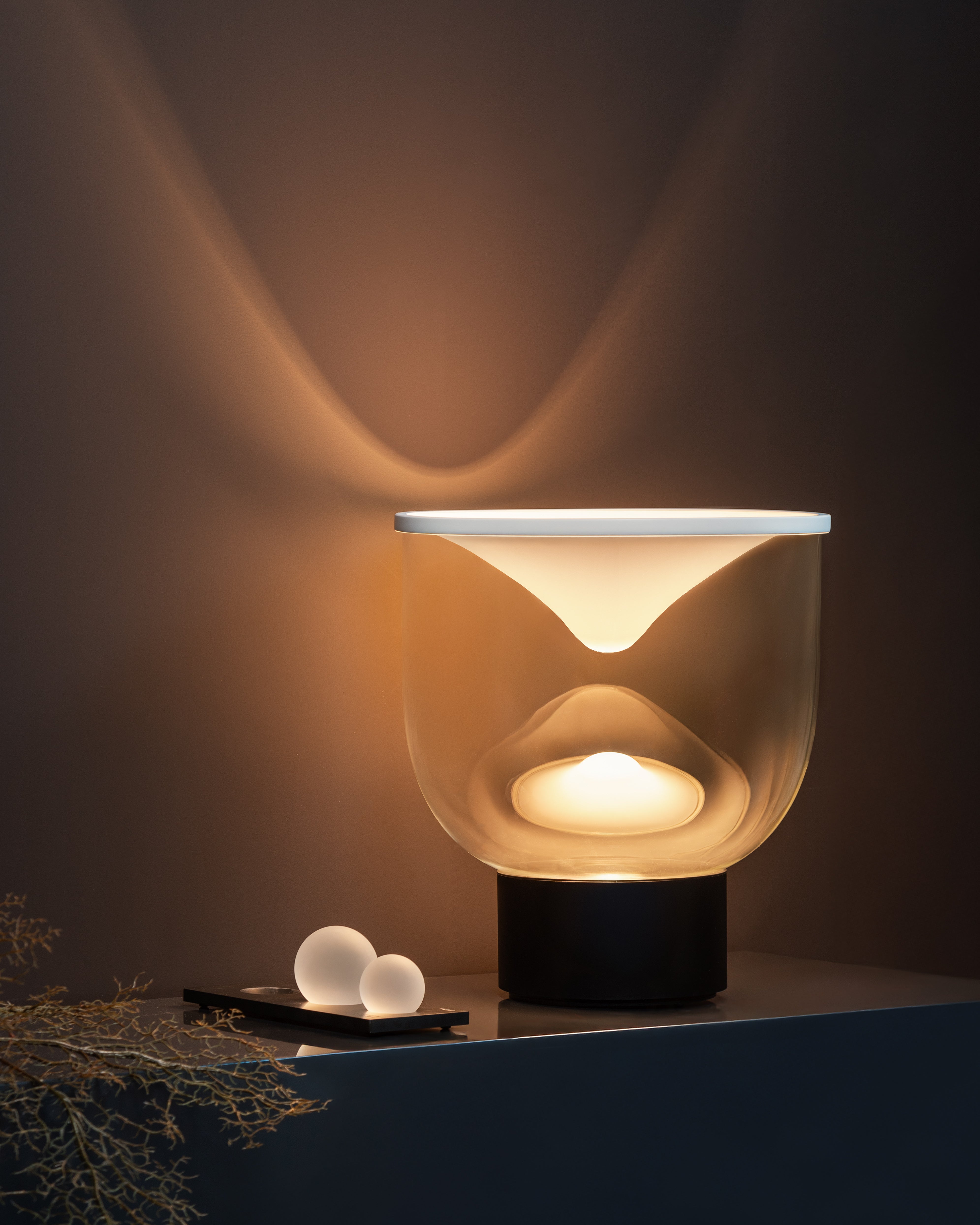Stolní lampa GRAMMOLUCE se skleněným stínidlem a černým podstavcem.