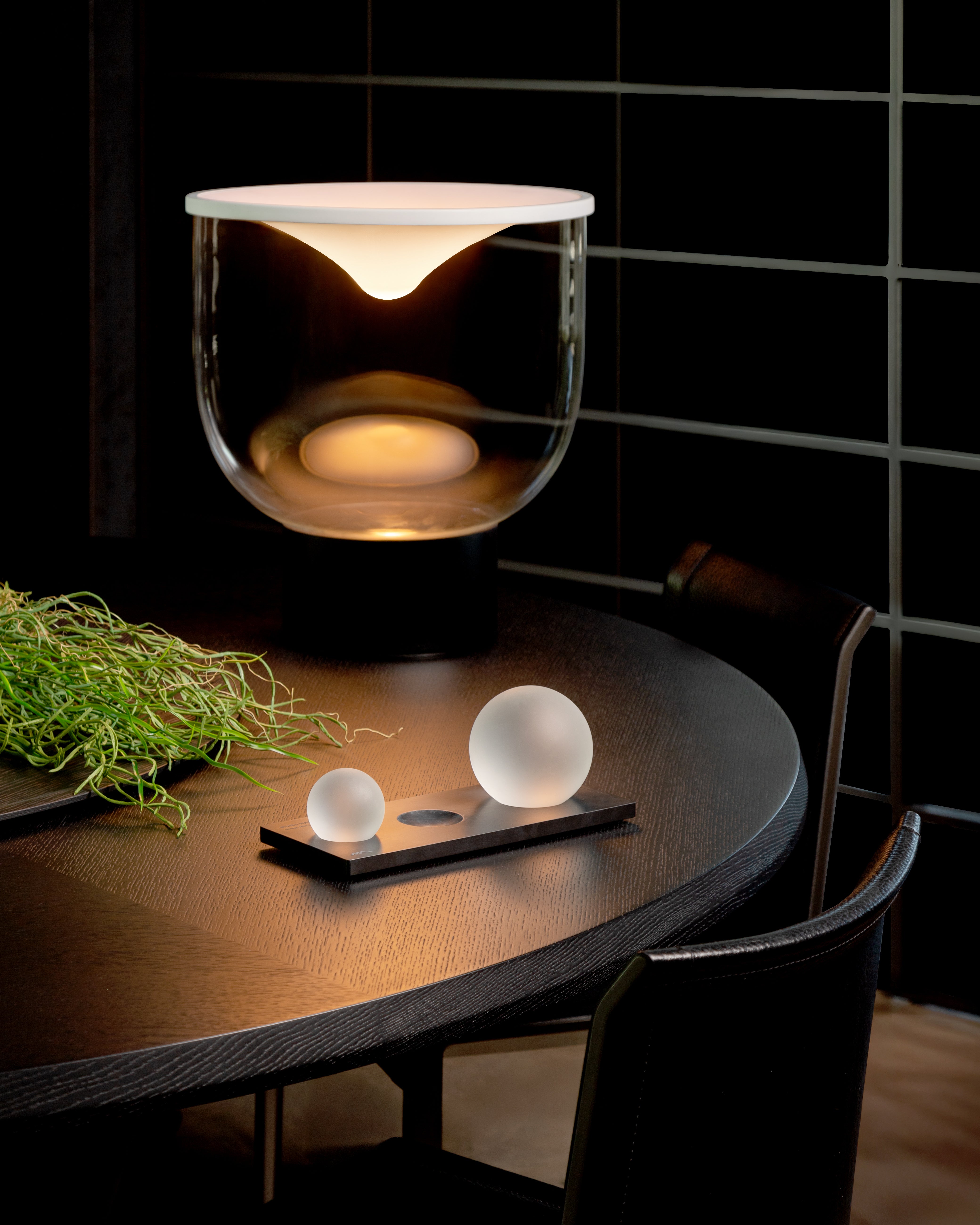 Stolní lampa GRAMMOLUCE se skleněným stínidlem a černým podstavcem.