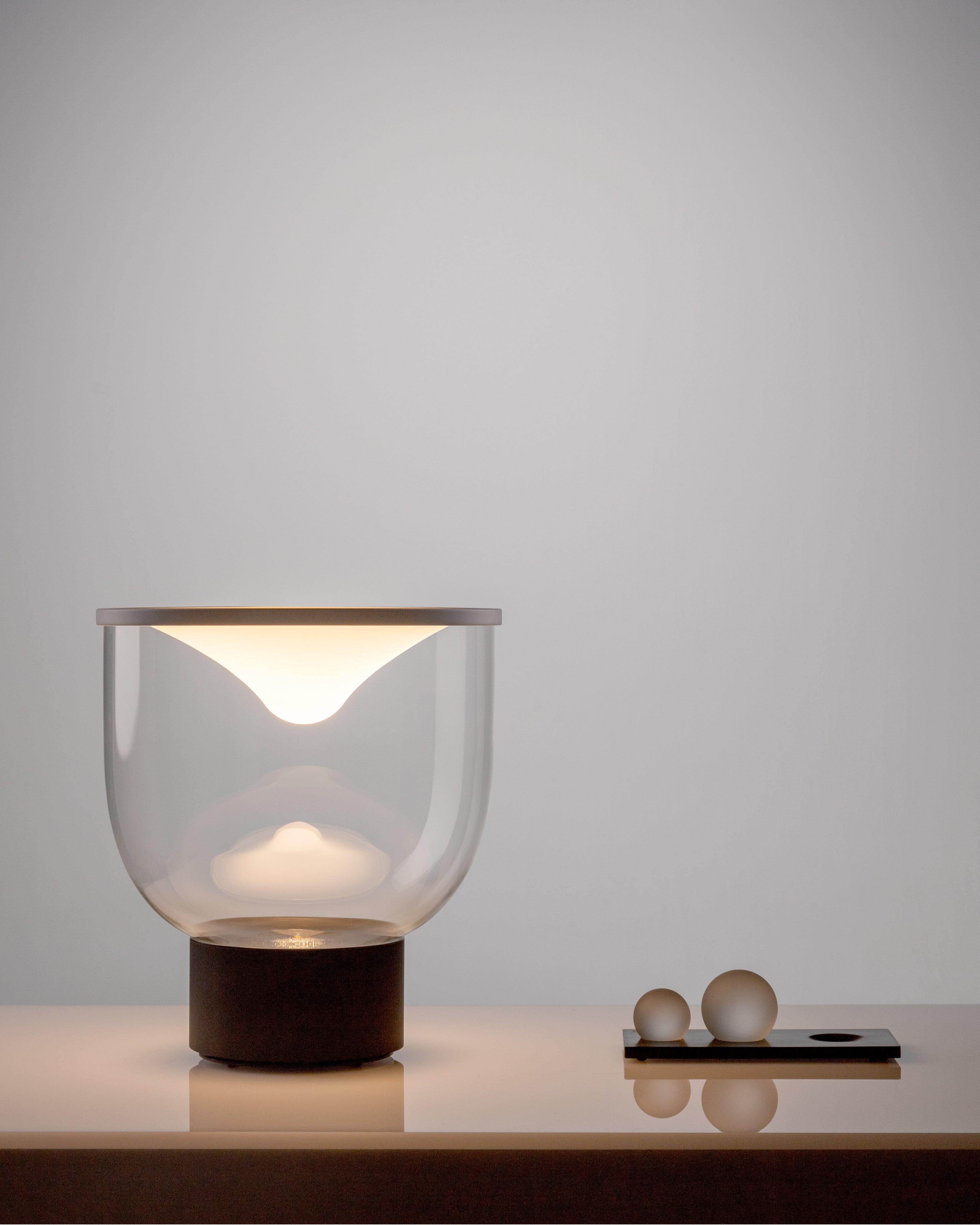 Stolní lampa GRAMMOLUCE se skleněným stínidlem a černým podstavcem.