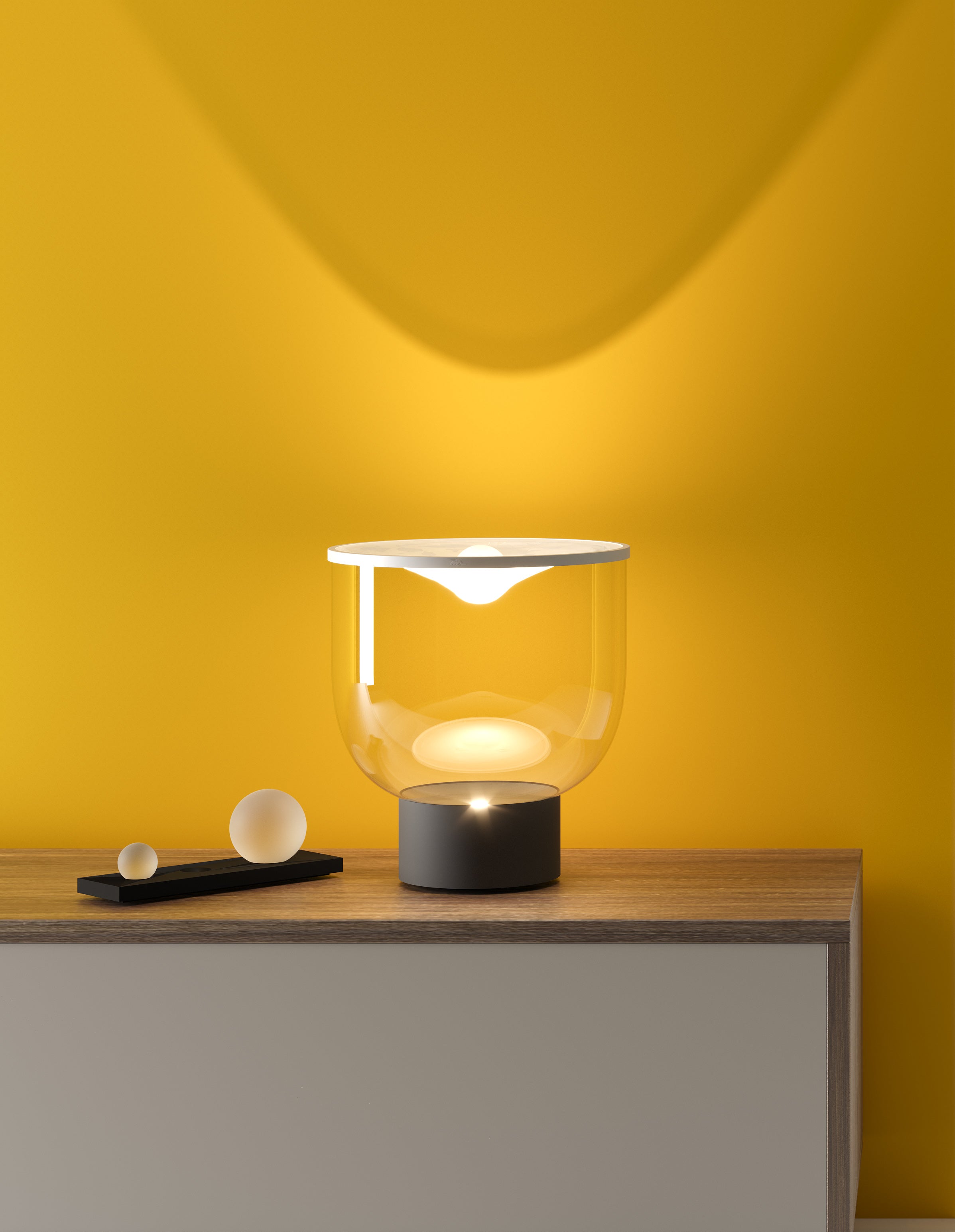 Stolní lampa GRAMMOLUCE se skleněným stínidlem a černým podstavcem.