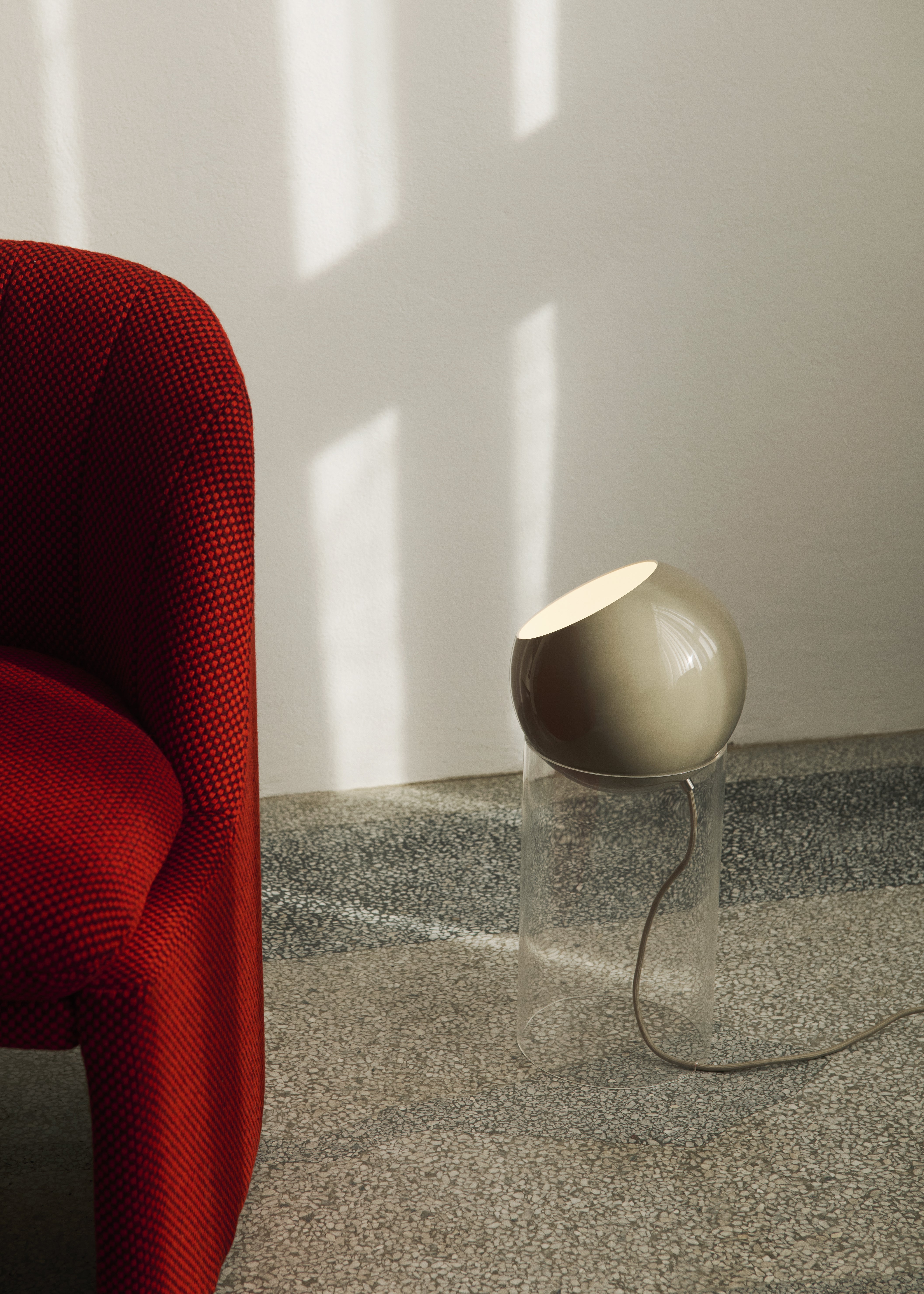 Stolní lampa TOPAN se šedobéžovým stínidlem a transparentním podstavcem.